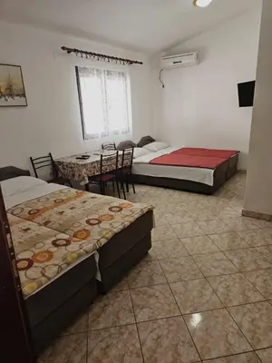 a room with two beds and a table in it at Apartmani MIM in Bar