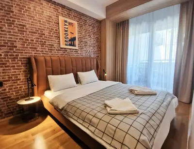 a bedroom with a large bed with a brick wall at Cozy One-Bedroom Apartment at Ljubovic Park in Podgorica