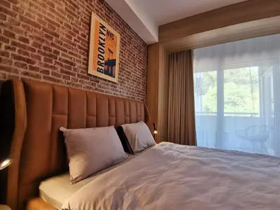 a bedroom with a large bed with a brick wall at Cozy One-Bedroom Apartment at Ljubovic Park in Podgorica