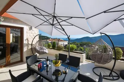 a table and chairs on a balcony with an umbrella at Villa Gradina in Budva