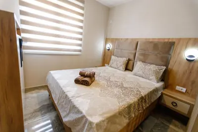 a bedroom with a large bed with a wooden headboard at Apartments Posejdon Lux in Utjeha