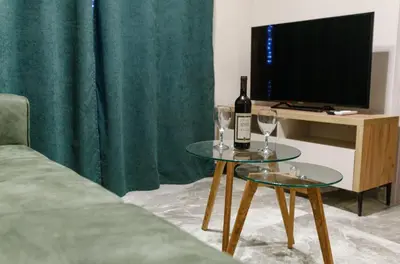 a living room with two tables with wine glasses and a television at Apartments Posejdon Lux in Utjeha