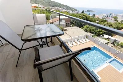 a balcony with a table and a swimming pool at Apartments Posejdon Lux in Utjeha