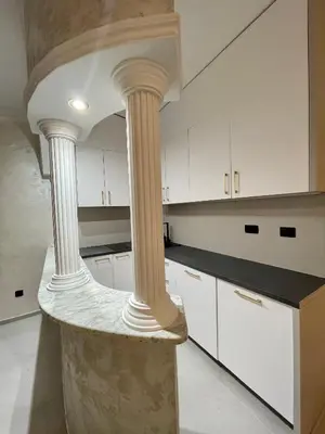 a kitchen with white cabinets and white columns at Budva house Maja in Budva