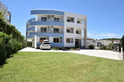 a white building with a car parked in front of it at Apartments Fati & Flori in Ulcinj