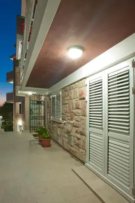 a building with a stone wall with shutters on it at Apartments Marina in Sveti Stefan