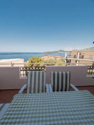 a table and chairs on a balcony with the ocean at Apartments Marina in Sveti Stefan