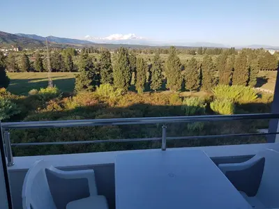a table and chairs on a balcony with a view of trees at Dina & Dona in Ulcinj