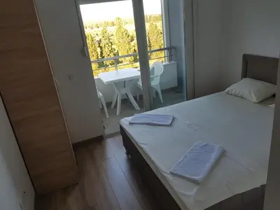 a bedroom with a bed and a balcony with a table at Dina & Dona in Ulcinj