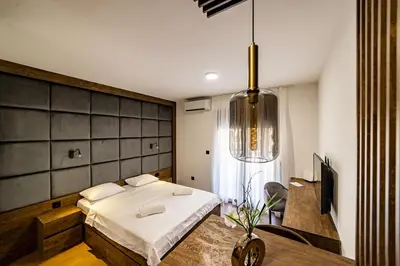 a bedroom with a bed and a desk and a television at Apartments Tulip Podgorica in Podgorica