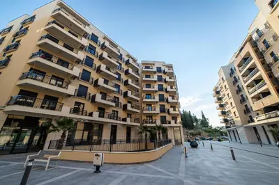 a large apartment building with palm trees in front of it at Apartments Tulip Podgorica in Podgorica