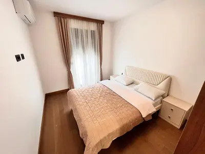 a small bedroom with a bed and a window at Apartments Tulip Podgorica in Podgorica