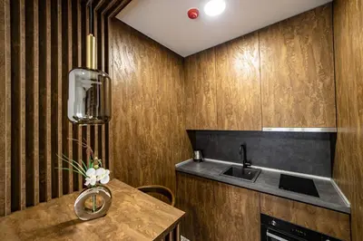a kitchen with wooden walls and a table with a sink at Apartments Tulip Podgorica in Podgorica