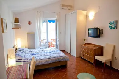 a bedroom with a bed and a dresser and a television at Apartments Mandarina Garden in Petrovac na Moru