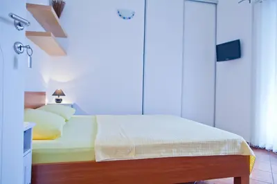 a bedroom with a bed with white sheets and yellow pillows at Apartments Mandarina Garden in Petrovac na Moru
