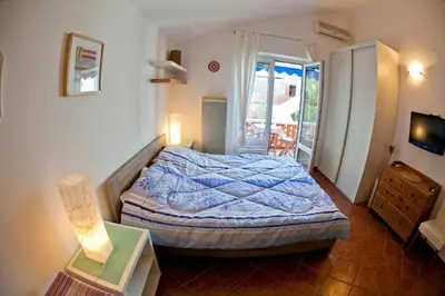 a bedroom with a bed and a television and a balcony at Apartments Mandarina Garden in Petrovac na Moru