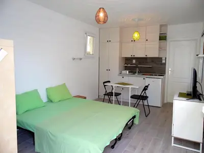 a bedroom with a green bed and a kitchen at Apartments Mandarina Garden in Petrovac na Moru
