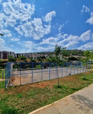 a tennis court with a fence on a tennis court at Riverside Apartment in Podgorica