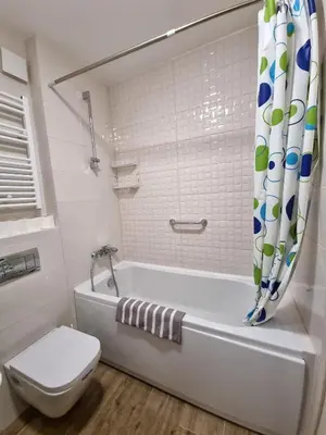 a white bathroom with a tub and a toilet at Riverside Apartment in Podgorica