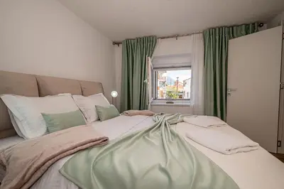 a bedroom with a large bed with green curtains at N&N Lux Guest house in Bar
