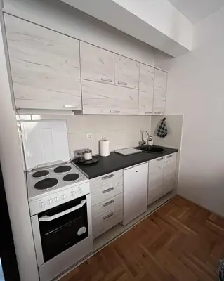 a small kitchen with a stove and white cabinets at Studio Place 8 in Podgorica