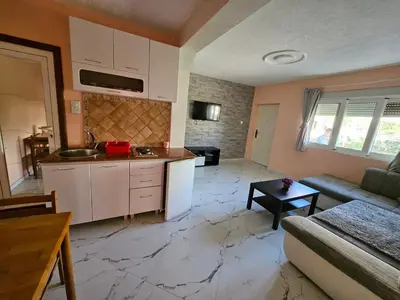a kitchen and living room with a couch and a table at Apartments Bulatović in Bar