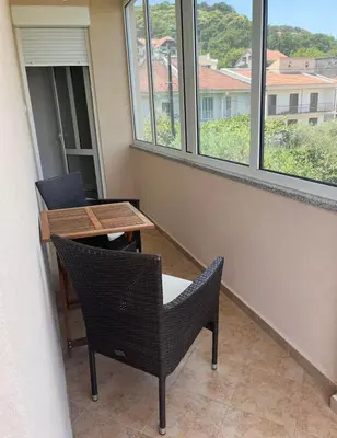a balcony with a table and chairs and windows at Duraku Apartment in Ulcinj