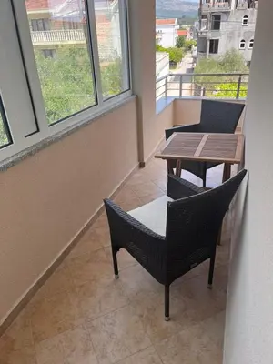 a table and chairs in a room with windows at Duraku Apartment in Ulcinj