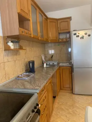 a kitchen with a white refrigerator and wooden cabinets at Duraku Apartment in Ulcinj