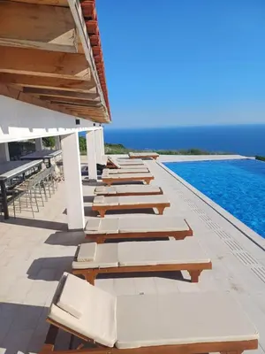 a row of chaise lounge chairs on a swimming pool at Villa Harizma in Budva