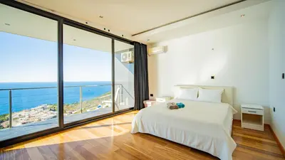 a bedroom with a white bed and large windows at Villa Harizma in Budva