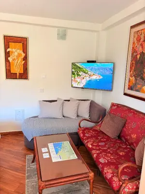 a living room with a couch and a tv on the wall at El Sol Apartmani in Bar