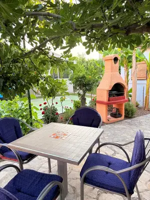 a table and chairs with a fireplace in a yard at El Sol Apartmani in Bar
