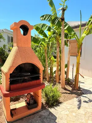 a outdoor pizza oven in a yard with trees at El Sol Apartmani in Bar