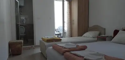 a bedroom with two beds and a bathroom with a shower at Apartmani Jacimovic in Čanj