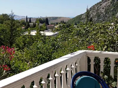 a white balcony with a blue chair and flowers at Vesela vila in Sutomore