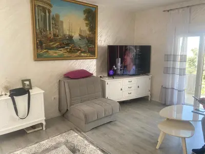 a living room with a chair and a tv at Apartman Lara in Sveti Stefan