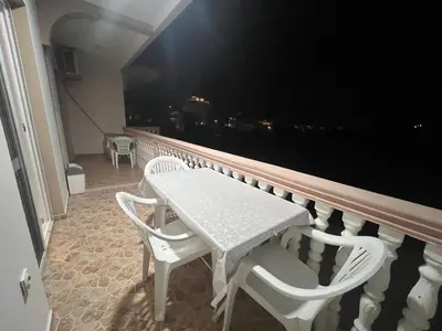 a white table and chairs on a balcony at night at K&K Apartments 1 in Ulcinj