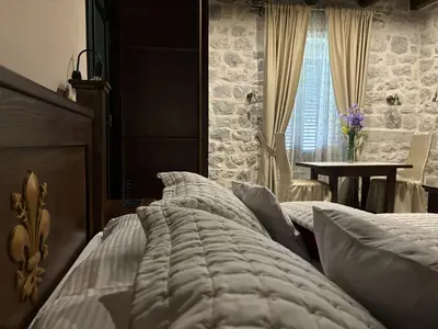 a bedroom with a bed and a table and a window at KAŽIN supreme in Kotor