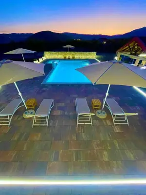 a pool with chairs and umbrellas in front of it at Cosy Cottage with Private Pool - Andrej in Danilovgrad