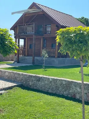 a log house with a stone wall in front of it at Cosy Cottage with Private Pool - Andrej in Danilovgrad