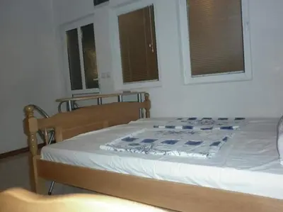 a bed in a bedroom with two windows at Bojana Blue Retreat in Ulcinj