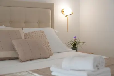 a bed with white sheets and pillows and a lamp at Mar nero Apartments in Bregvija