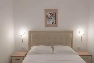 a bedroom with a white bed with two tables and two lights at Mar nero Apartments in Bregvija