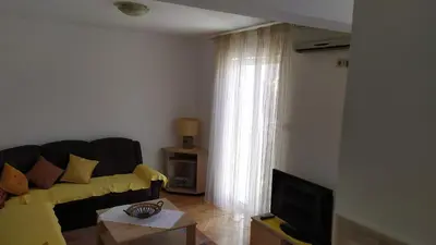 a living room with a yellow couch and a television at FLAT FOR RENT MARINOVIC in Budva
