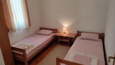 two beds in a room with a table and a lamp at FLAT FOR RENT MARINOVIC in Budva