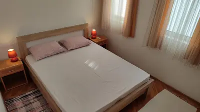 a small bedroom with a white bed with two candles at FLAT FOR RENT MARINOVIC in Budva