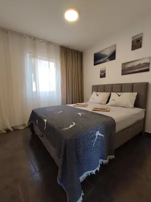 a bedroom with a bed with a blue blanket on it at Sayohat Apartments in Dobra Voda