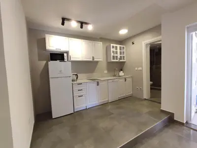 a kitchen with white cabinets and a white refrigerator at Sayohat Apartments in Dobra Voda