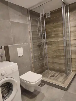 a bathroom with a shower and a toilet and a washing machine at Sayohat Apartments in Dobra Voda